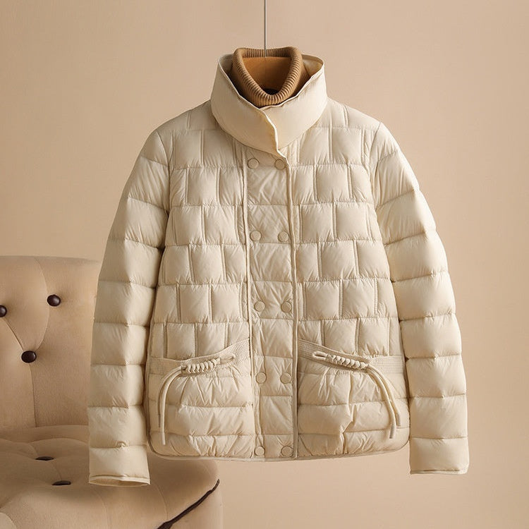 Beige Daunenjacke mit Stehkragen, gestepptem Design und Taschen, hängend vor neutralem Hintergrund. Wintermode, warme Oberbekleidung.