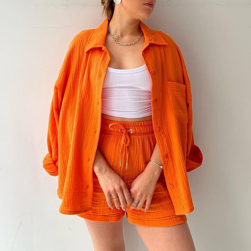 Frau in orangefarbenem Freizeit-Set mit Hemd und Shorts, weißem Top, modischem Look, Sommermode, lässiger Stil, trendige Damenbekleidung.