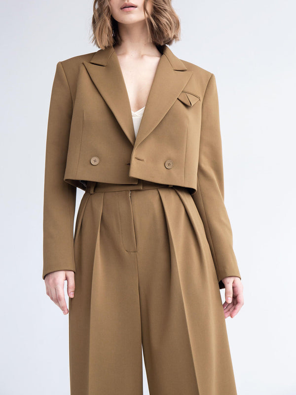 Frau in braunem, maßgeschneidertem Anzug mit kurzem Blazer und weiten Hosen, modisch elegant, Business-Outfit, minimalistisch, zeitgenössische Mode.