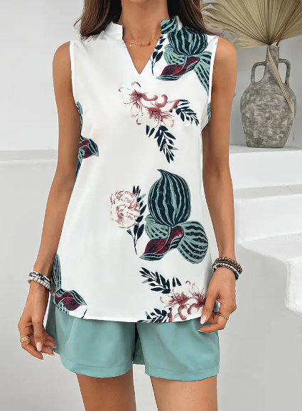Frau trägt ärmellose weiße Bluse mit floralem Muster und grüne Shorts. Sommermode, lässiger Stil, elegantes Design, Freizeitkleidung.