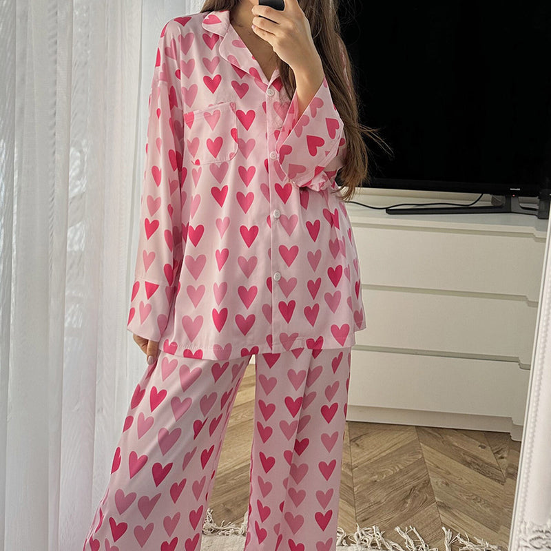 Frau in rosa Pyjama mit Herzmuster steht in modernem Schlafzimmer. Bequeme Nachtwäsche, stilvolles Design, gemütliche Atmosphäre.