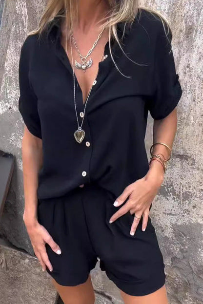 Frau in schwarzem, lockerem Sommeroutfit mit kurzen Ärmeln und Shorts, trägt lange Halsketten. Modetrend, lässiger Stil, Sommermode.