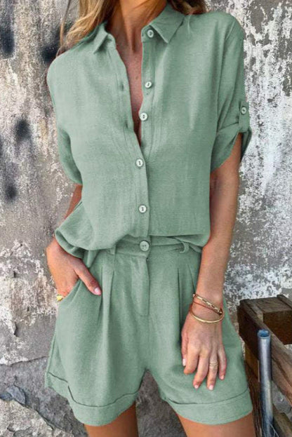 Frau in grünem Leinen-Shorts-Set vor rustikaler Wand. Sommermode, lässiger Stil, Damenbekleidung, trendiges Outfit, Freizeitlook.