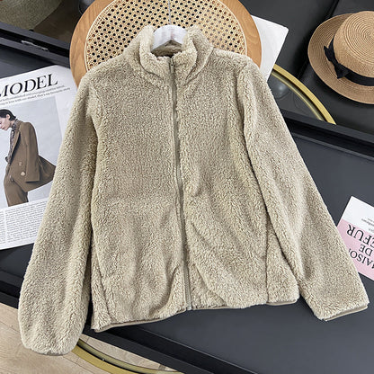 Beige Fleecejacke mit Reißverschluss auf schwarzem Tisch, neben Modezeitschrift und Strohhut. Kuschelige Damenjacke, ideal für Herbstmode.