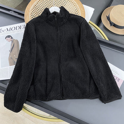 Schwarze Fleecejacke auf Tisch, umgeben von Zeitschriften und Strohhut. Modische, warme Jacke für Herbst und Winter. Ideal für Outdoor-Aktivitäten.