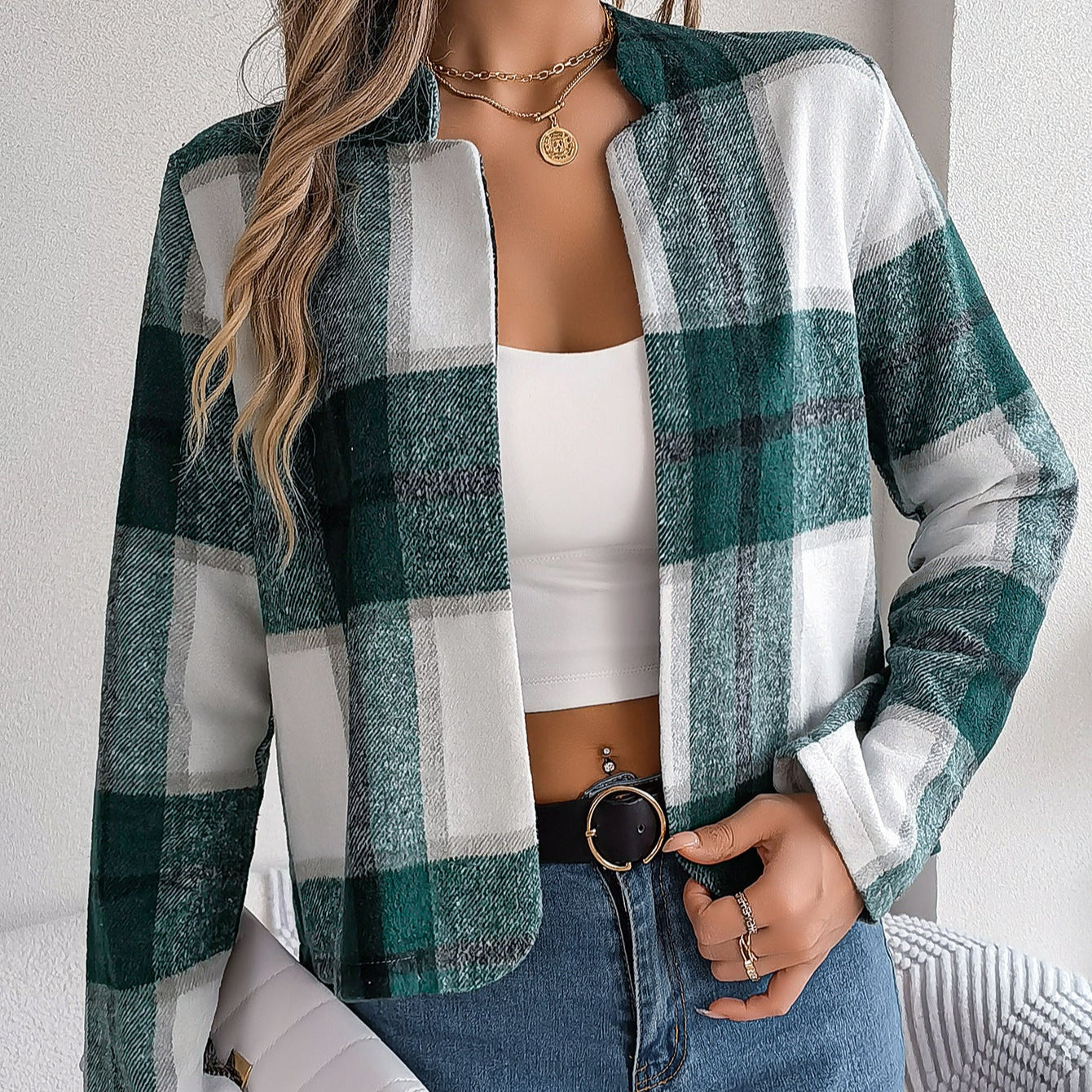 Frau trägt grün-weiß karierte Jacke, weißes Top und Jeans. Modetrend, lässiger Look, Herbstmode, Damenbekleidung, stilvolles Outfit.