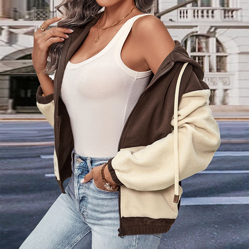 Frau in modischer zweifarbiger Fleecejacke, weißem Tanktop und Jeans vor städtischer Kulisse. Trendige Damenmode, Herbst/Winter-Look.