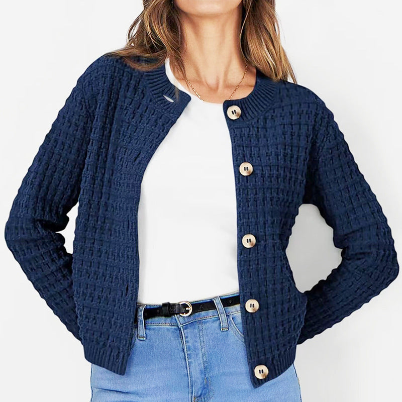Frau trägt dunkelblauen Strick-Cardigan mit Knöpfen, kombiniert mit weißem T-Shirt und blauer Jeans. Modischer Damen-Look, Herbstmode.