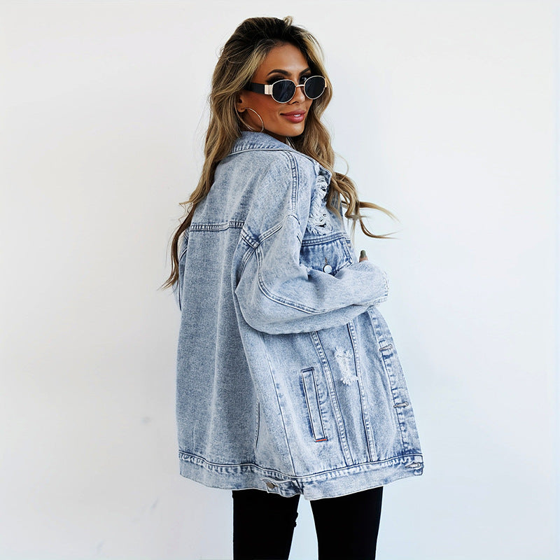 Frau in übergroßer Jeansjacke, Sonnenbrille und langen Haaren, modisch, lässiger Stil, weiße Wand, Streetwear-Trend, Denim-Look.