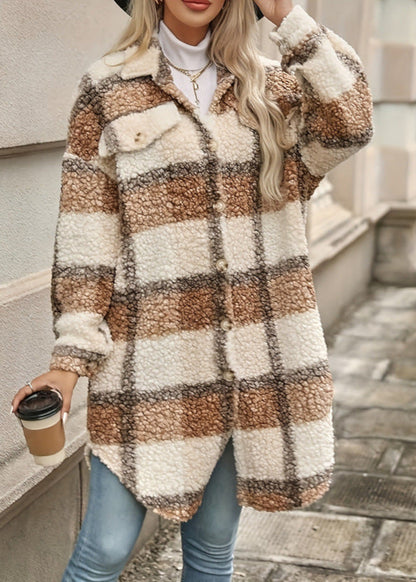 Frau in kariertem Teddy-Mantel, hält Kaffeebecher, trägt Jeans und Hut. Modetrend Herbst/Winter, gemütlicher Streetstyle-Look.
