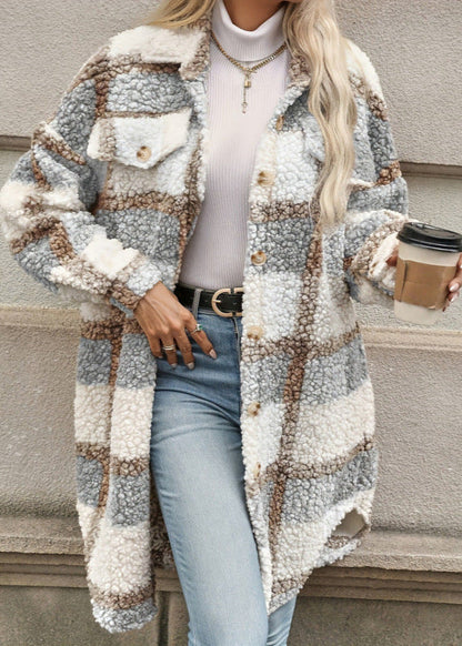 Frau in kariertem Teddy-Mantel, weißem Rollkragenpullover und blauer Jeans hält Kaffeebecher. Modetrend Herbst/Winter, lässiger Streetstyle.