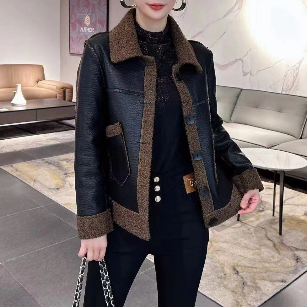 Frau in schwarzer Lederjacke mit braunem Kragen und Manschetten, schwarze Hose, moderne Inneneinrichtung, stilvolle Mode, elegantes Design.