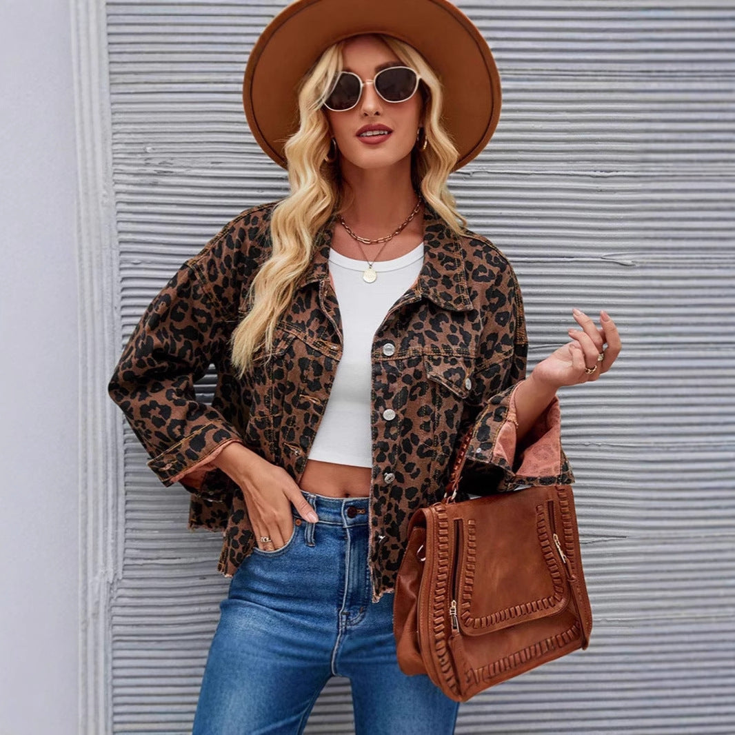 Blonde Frau mit Sonnenbrille, Hut und Leopardenjacke, trägt braune Tasche und Jeans vor gestreifter Wand. Modetrends, Damenmode, Streetstyle.