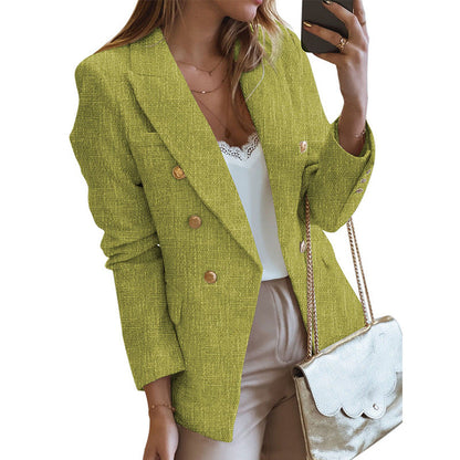 Frau in grünem Blazer mit goldenen Knöpfen, weißem Top und beiger Hose, hält goldene Handtasche. Elegante Damenmode, Business-Look.