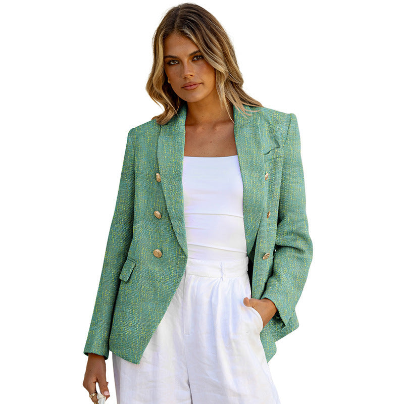 Frau in grünem Blazer mit goldenen Knöpfen, weißem Top und weißer Hose. Modetrend, Damenmode, eleganter Look, stilvolle Kleidung.