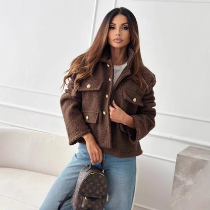 Eine Frau in brauner Jacke und blauer Jeans hält eine Louis Vuitton Tasche. Mode, Luxus, Damenbekleidung, Herbststil, Designer-Accessoires.