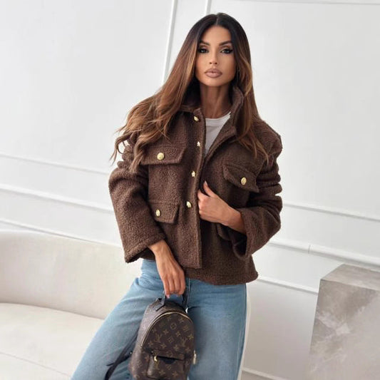 Eine Frau in brauner Jacke und blauer Jeans hält eine Louis Vuitton Tasche. Mode, Luxus, Damenbekleidung, Herbststil, Designer-Accessoires.