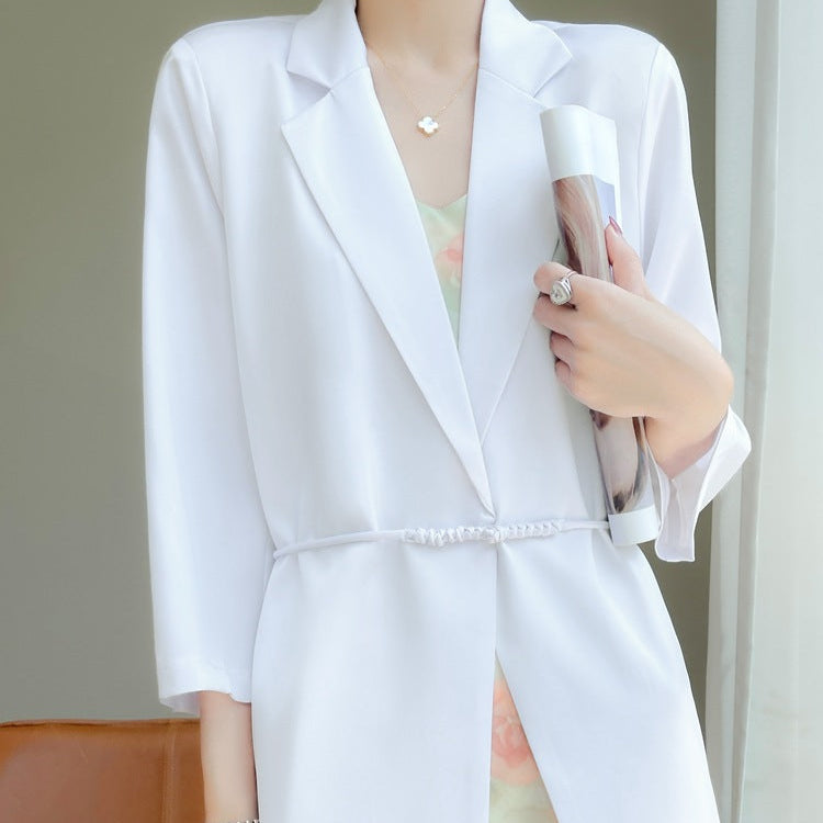 Frau in elegantem weißen Blazer, hält Zeitschrift, modisches Outfit, minimalistisch, Business-Look, stilvolle Kleidung, modernes Design.