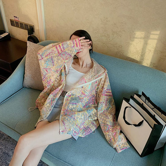 Frau auf Sofa mit bunter, glitzernder Jacke, hält Hand vor Gesicht. Neben ihr Einkaufstaschen. Moderne Mode, lässiger Stil, Innenraum.