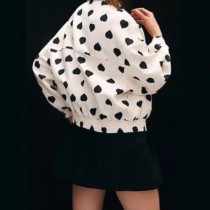 Weiße Jacke mit schwarzen Herzmustern, kombiniert mit schwarzem Rock. Modetrend, stilvolle Damenbekleidung, auffälliges Design.