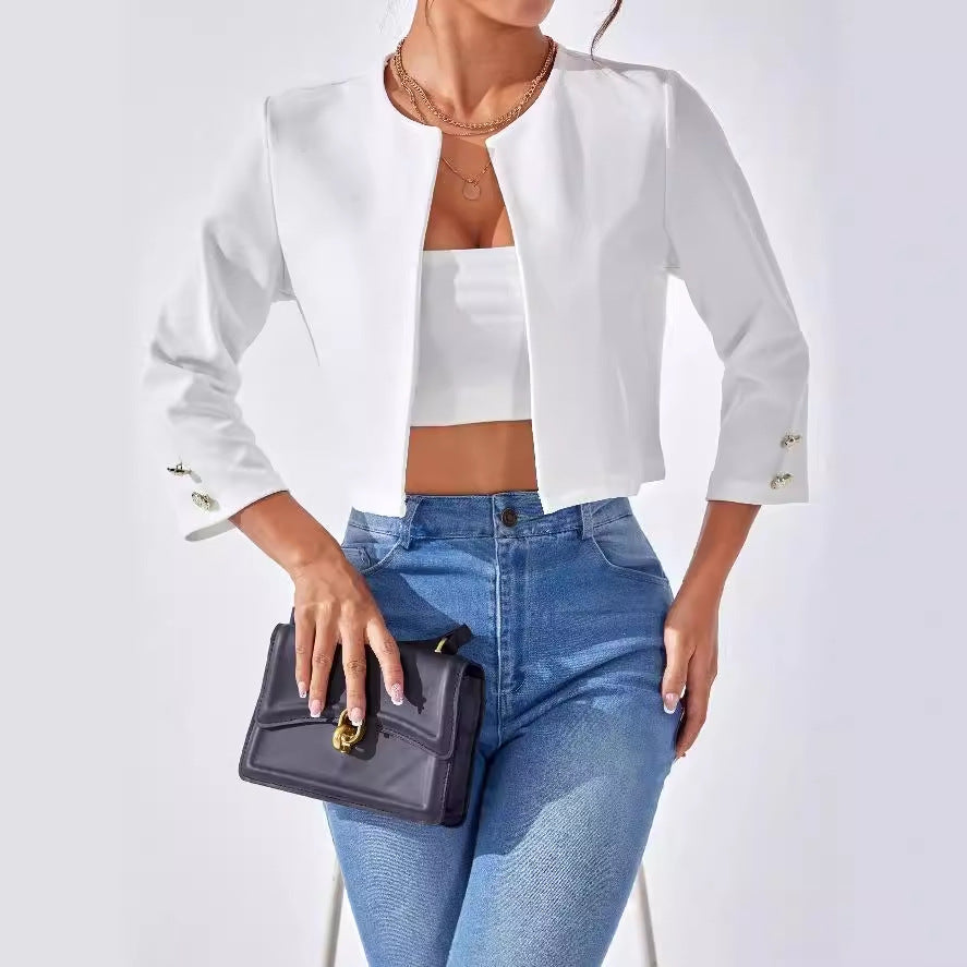 Frau in weißem Blazer und blauer Jeans, hält schwarze Handtasche. Modetrend, elegante Damenbekleidung, stilvolles Outfit.