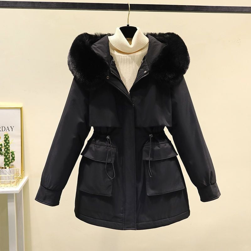 Schwarze Damenwinterjacke mit Kapuze und Kunstfellbesatz, Taillenzug, zwei Taschen, auf Kleiderbügel vor beigem Hintergrund.