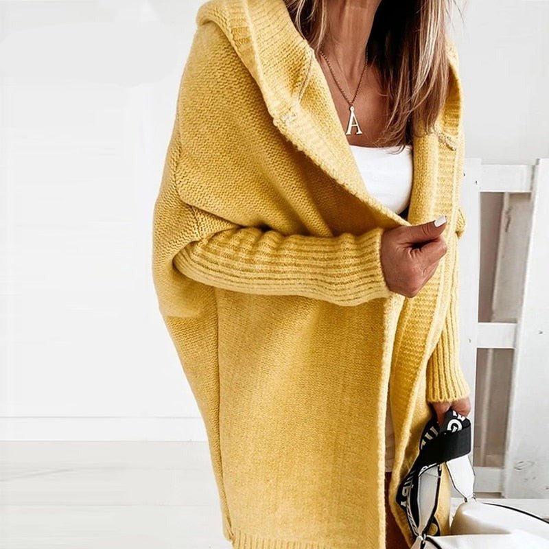 Frau in gelbem Strick-Cardigan mit Kapuze, weißem Top und Tasche. Modetrend, Herbstmode, Damenbekleidung, lässiger Stil.