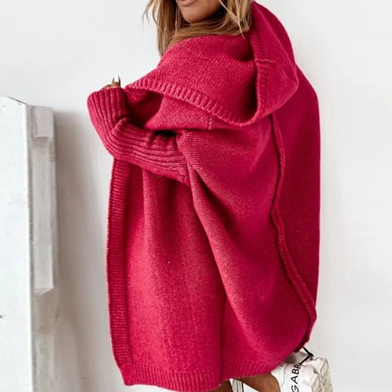 Frau in pinkem Strick-Cardigan mit Kapuze, seitlich fotografiert. Modetrend, Damenmode, Herbstbekleidung, gemütlicher Oversize-Look.