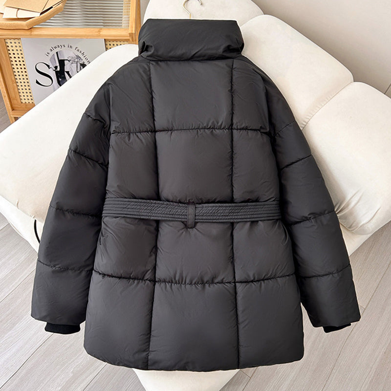 Schwarze Daunenjacke mit Gürtel auf weißem Sofa, modische Winterbekleidung, warme gesteppte Jacke, stilvoll und bequem für kalte Tage.