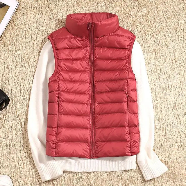 Rote Damen-Daunenweste auf weißem Pullover, modische Winterbekleidung, gesteppte Weste, warme Outdoor-Bekleidung, stilvoll und bequem.