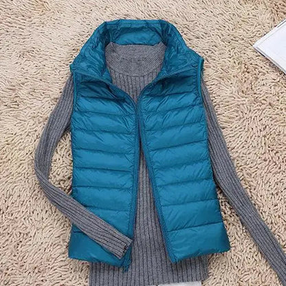 Blaue Daunenweste auf grauem Strickpullover, liegend auf beigem Teppich. Modische Winterkleidung, warm und stilvoll. Ideal für kalte Tage.