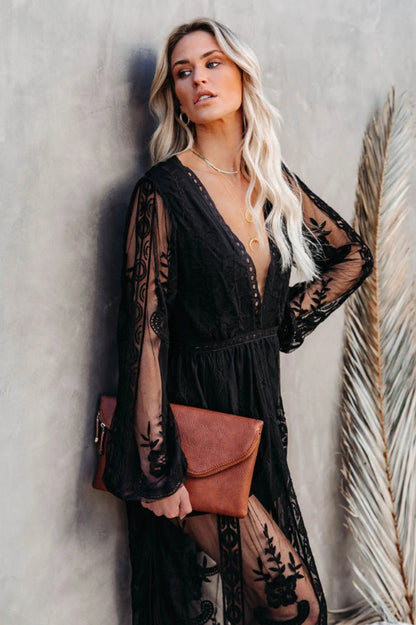 Blonde Frau in schwarzem Spitzenkleid lehnt an Wand, hält braune Clutch. Elegante Mode, Boho-Stil, Abendgarderobe, trendige Accessoires.