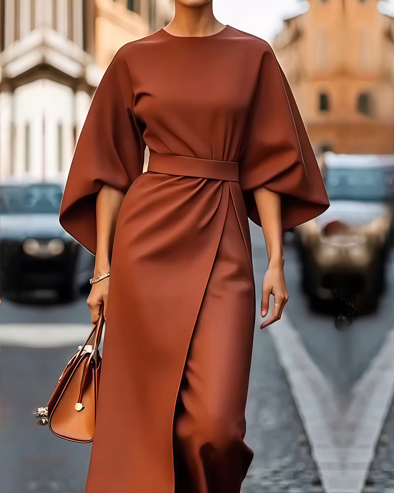 Elegante Frau in braunem Kleid mit weitem Schnitt und passender Handtasche, läuft auf einer Stadtstraße. Mode, Stil, urbane Eleganz.