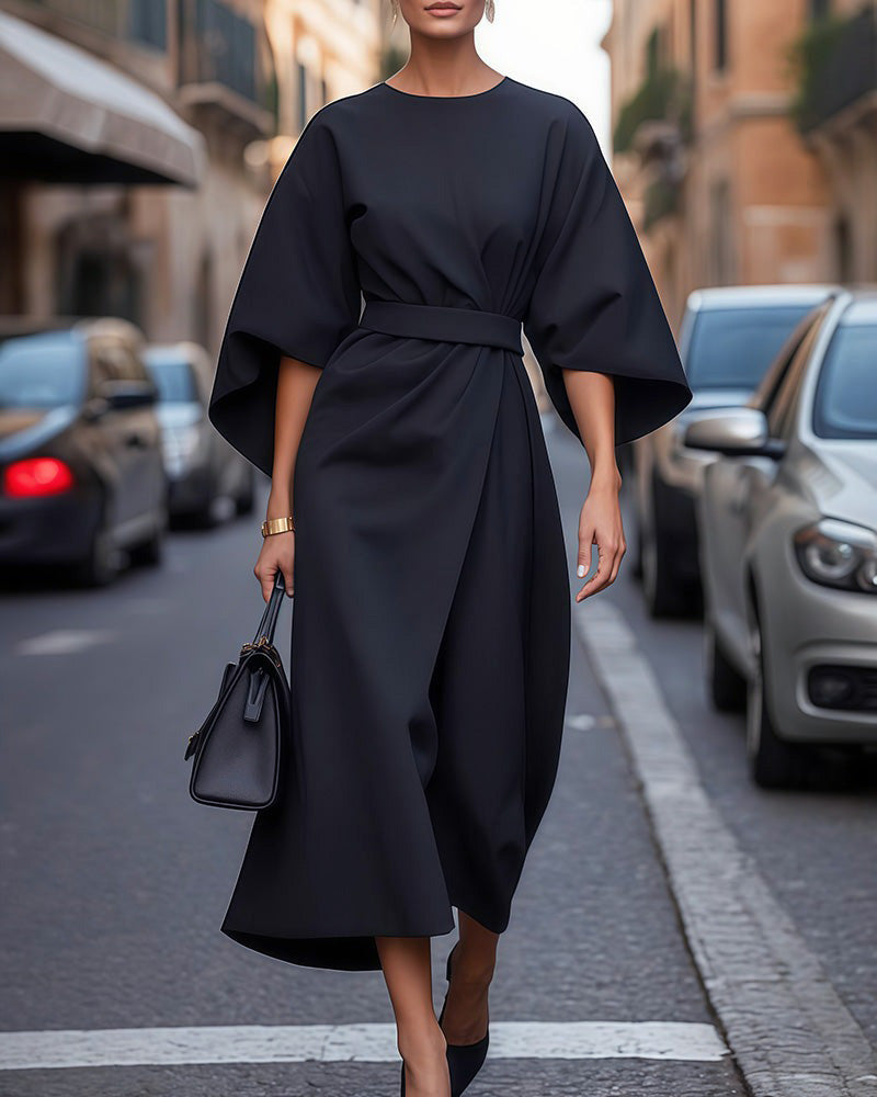 Elegante Frau in schwarzem Kleid auf Stadtstraße, trägt schwarze Handtasche. Mode, Streetstyle, urbane Eleganz, zeitloses Design.