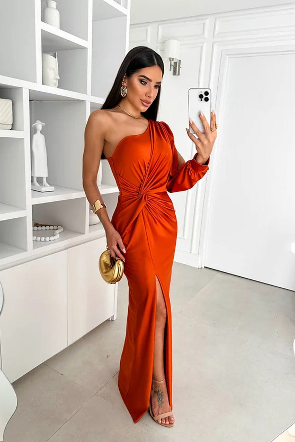 Frau in elegantem, einarmigem, orangefarbenem Abendkleid mit hohem Schlitz, posiert für Selfie. Perfekt für Abendmode, Glamour, Modefotografie.