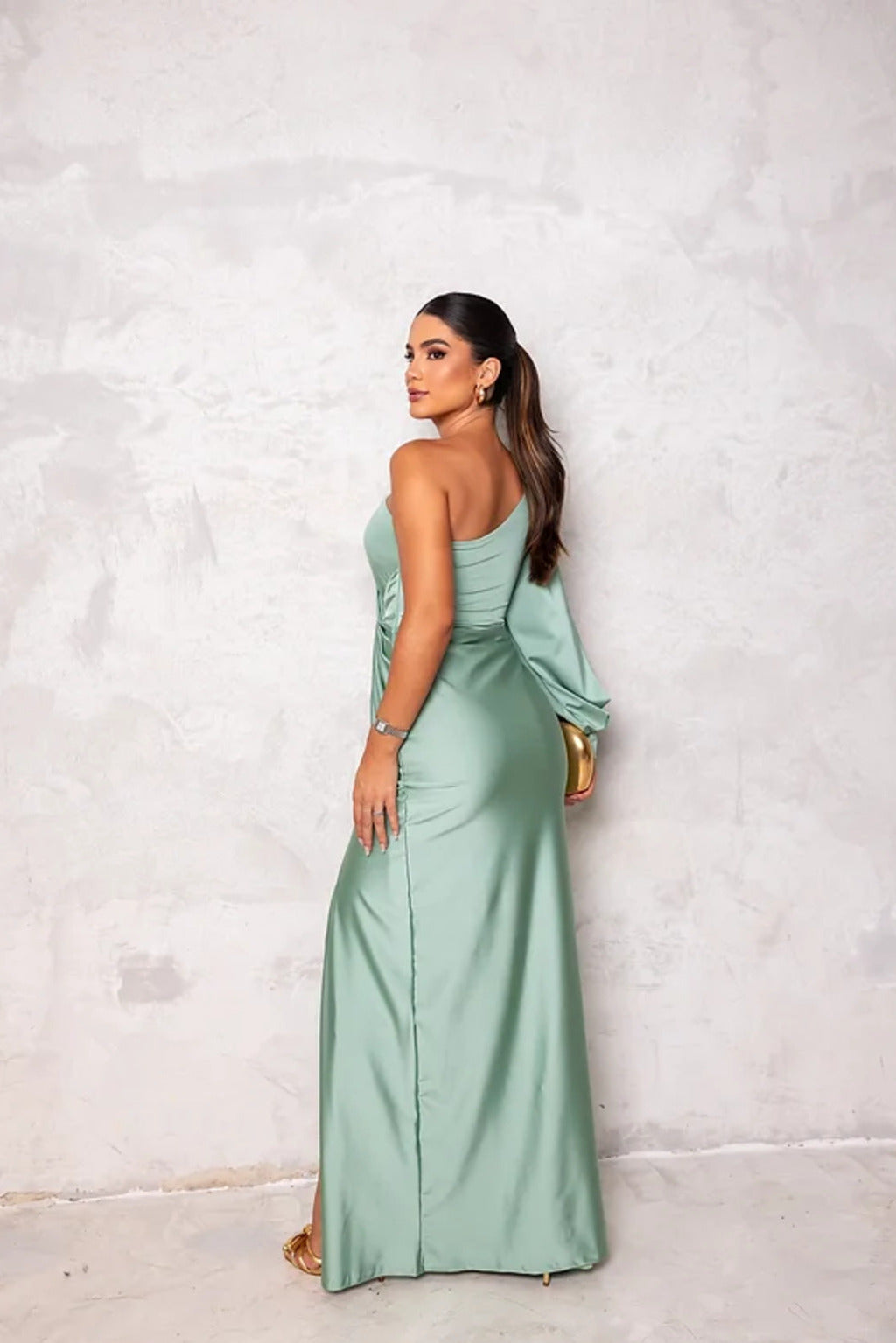 Frau in eleganter, mintgrüner Abendkleid, posiert vor grauer Wand. Stilvolle Mode, Abendgarderobe, glamouröser Look.
