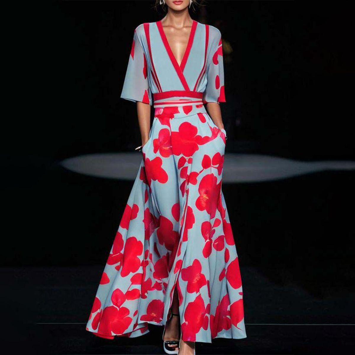 Frau in elegantem, blauem Kleid mit roten Blumenmustern, V-Ausschnitt und weiten Ärmeln auf Laufsteg. Modetrend, Abendmode, Designer-Kleid.