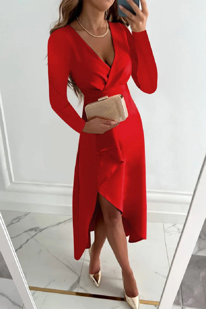 Frau im eleganten roten Kleid mit V-Ausschnitt, goldener Clutch und beigen High Heels, posiert vor einem Spiegel. Perfekt für Abendmode und Partys.