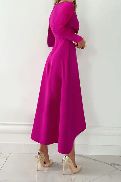 Frau in fuchsiafarbenem Kleid, seitlich stehend, mit goldenen High Heels auf Marmorboden. Elegantes Abendkleid, modische Damenmode.