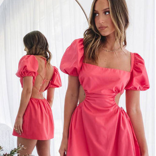 Frau in rotem Kleid mit Puffärmeln und Rückenausschnitt vor Spiegel. Modetrend, elegantes Abendkleid, stilvolle Damenmode.