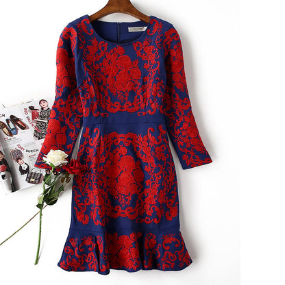 Blaues Kleid mit roten Blumenmustern, langärmelig, knielang, elegantes Design, auf einem Kleiderbügel, neben einer weißen Rose und Zeitschriften.