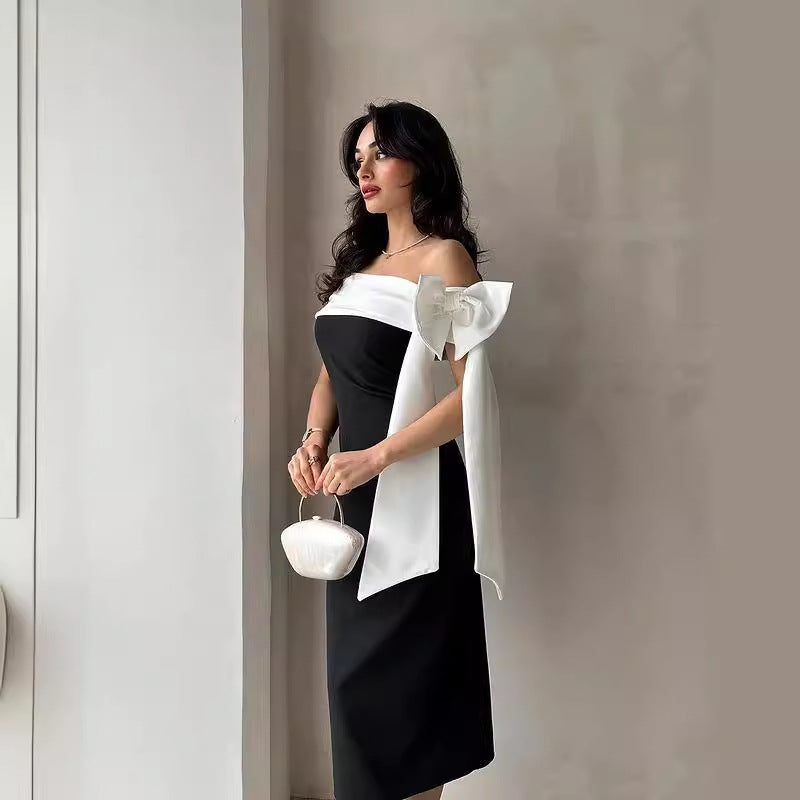 Schwarzes Abendkleid mit weißer Schleife, elegante Frau, stilvolle Mode, modernes Design, luxuriöse Handtasche, glamouröser Look, Abendmode.
