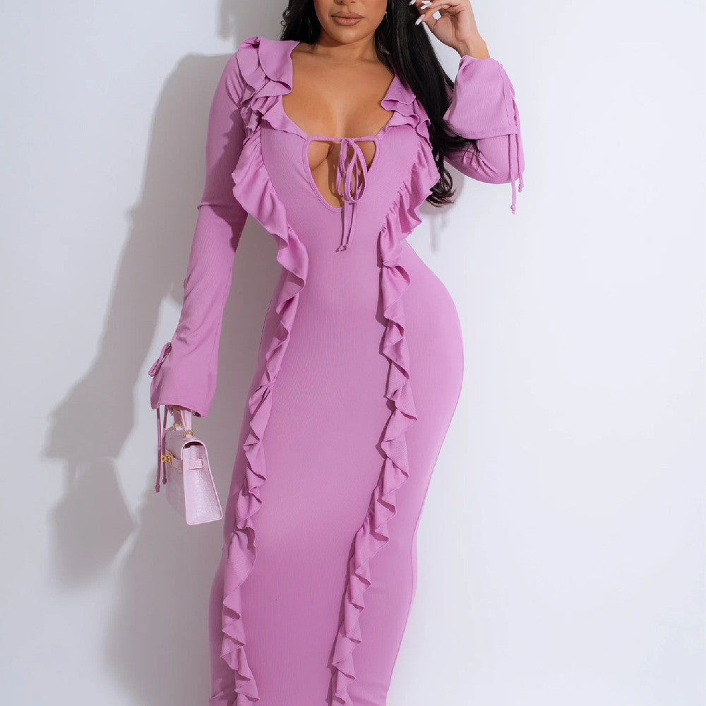 Frau in figurbetontem, rosa Rüschenkleid mit tiefem Ausschnitt, hält eine kleine rosa Handtasche. Elegante Mode, Abendkleid, stilvoller Look.