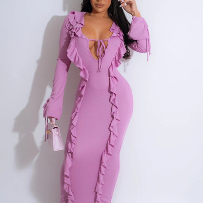 Frau in figurbetontem, rosa Rüschenkleid mit tiefem Ausschnitt, hält eine kleine rosa Handtasche. Elegante Mode, Abendkleid, stilvoller Look.