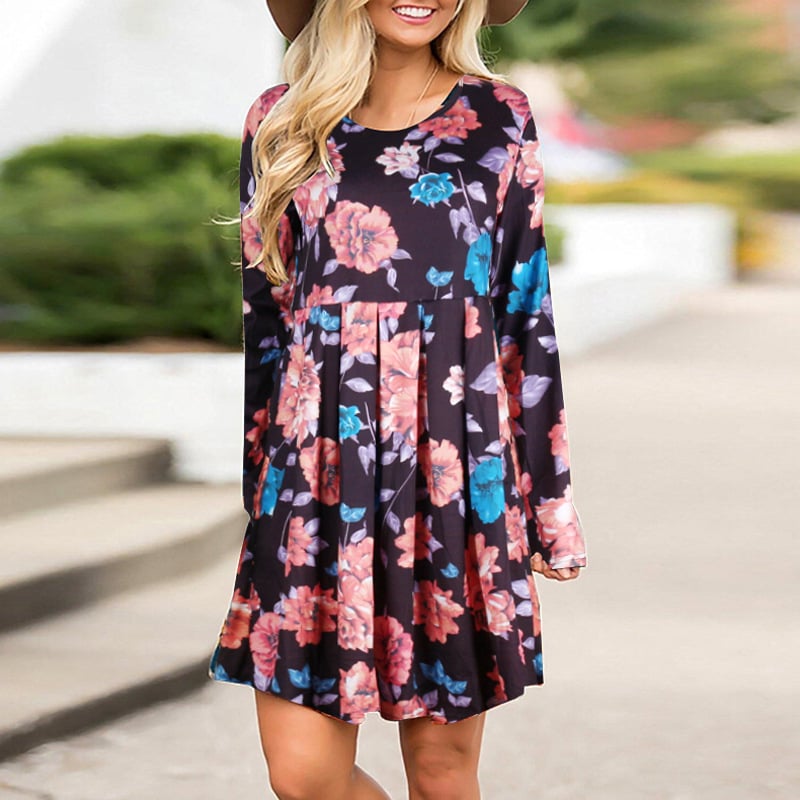 Frau in geblümtem Kleid mit langen Ärmeln und Hut, lächelnd im Freien. Modetrend, Damenmode, florales Design, Freizeitkleidung.