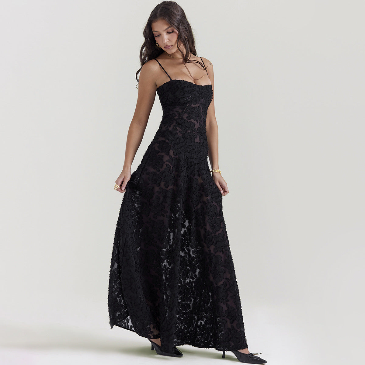 Frau in elegantem, schwarzem Spitzenkleid mit Spaghettiträgern, posiert vor neutralem Hintergrund. Abendmode, Damenkleider, stilvolle Abendgarderobe.