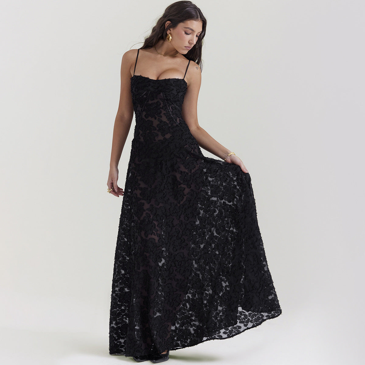 Frau in elegantem, schwarzem Spitzenkleid mit Spaghettiträgern, posiert vor neutralem Hintergrund. Abendmode, Damenkleidung, stilvoll.