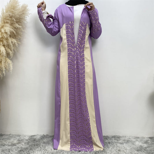 Frau in lila und cremefarbener Abaya mit Spitzenmuster, steht vor weißem Hintergrund. Modest Fashion, islamische Kleidung, elegantes Design.