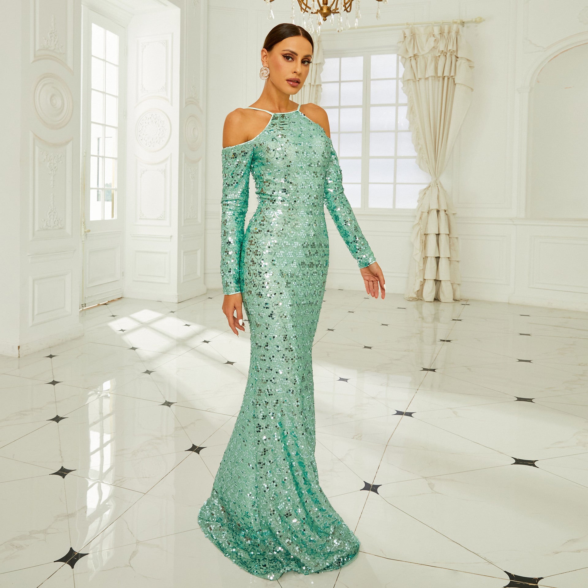 Elegantes Abendkleid in Türkis mit Pailletten, getragen von einer Frau in einem luxuriösen, hellen Raum mit Marmorboden und Kronleuchter.