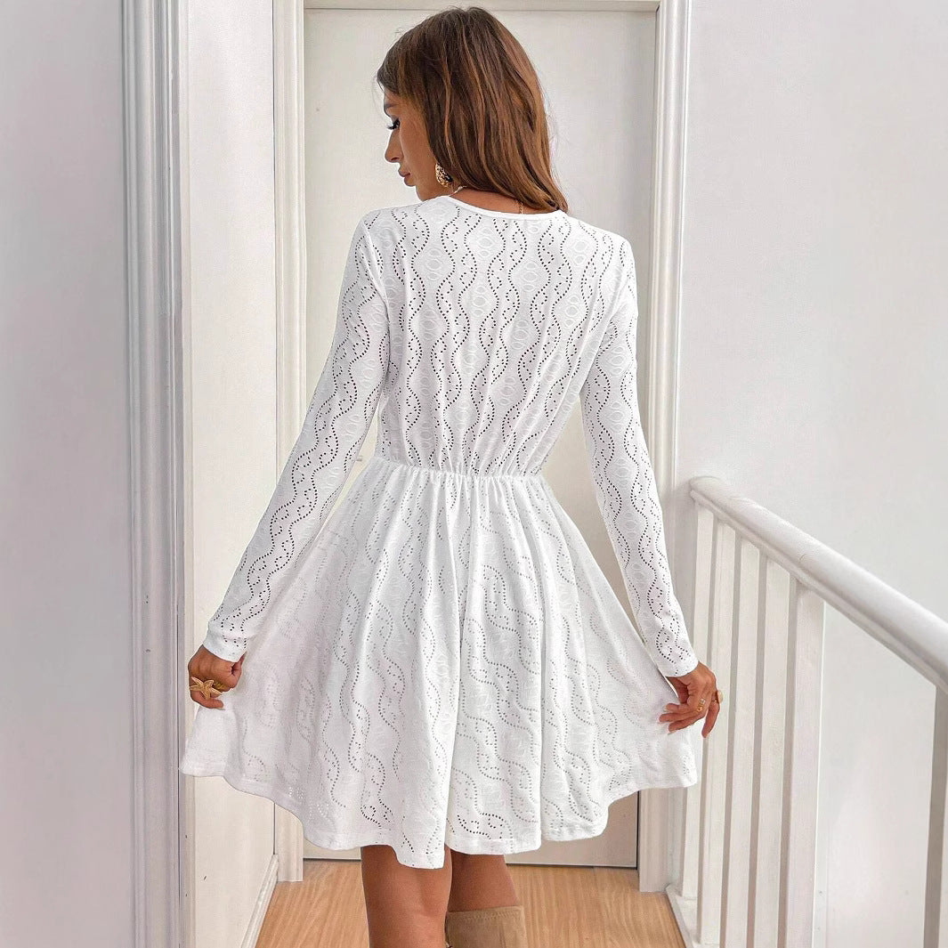 Frau in weißem Spitzenkleid, Rückansicht, steht in modernem Innenraum. Elegantes Design, lange Ärmel, modische Damenbekleidung, stilvoller Look.